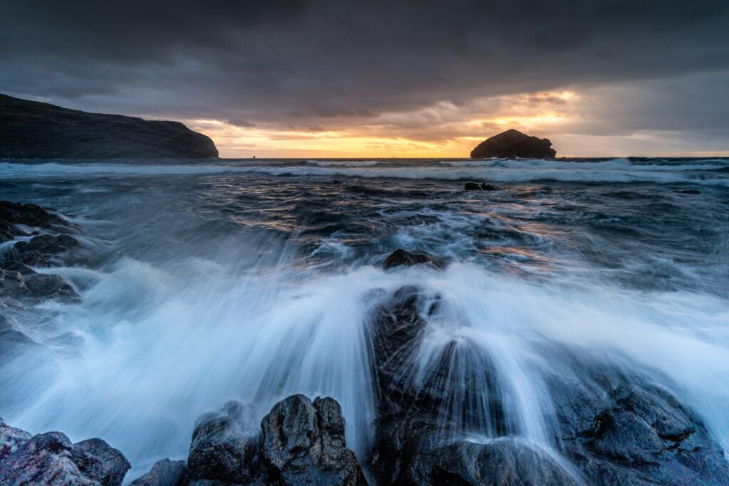 Crashing waves on rocky shore at sunset