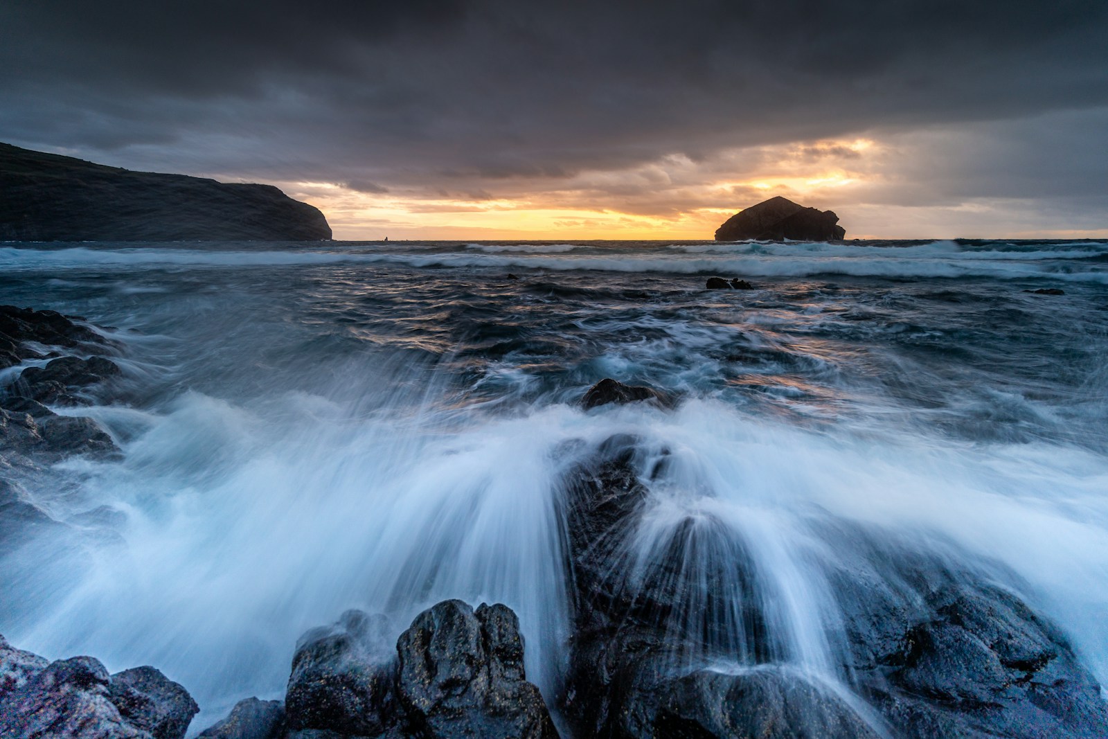 Crashing waves on rocky shore at sunset